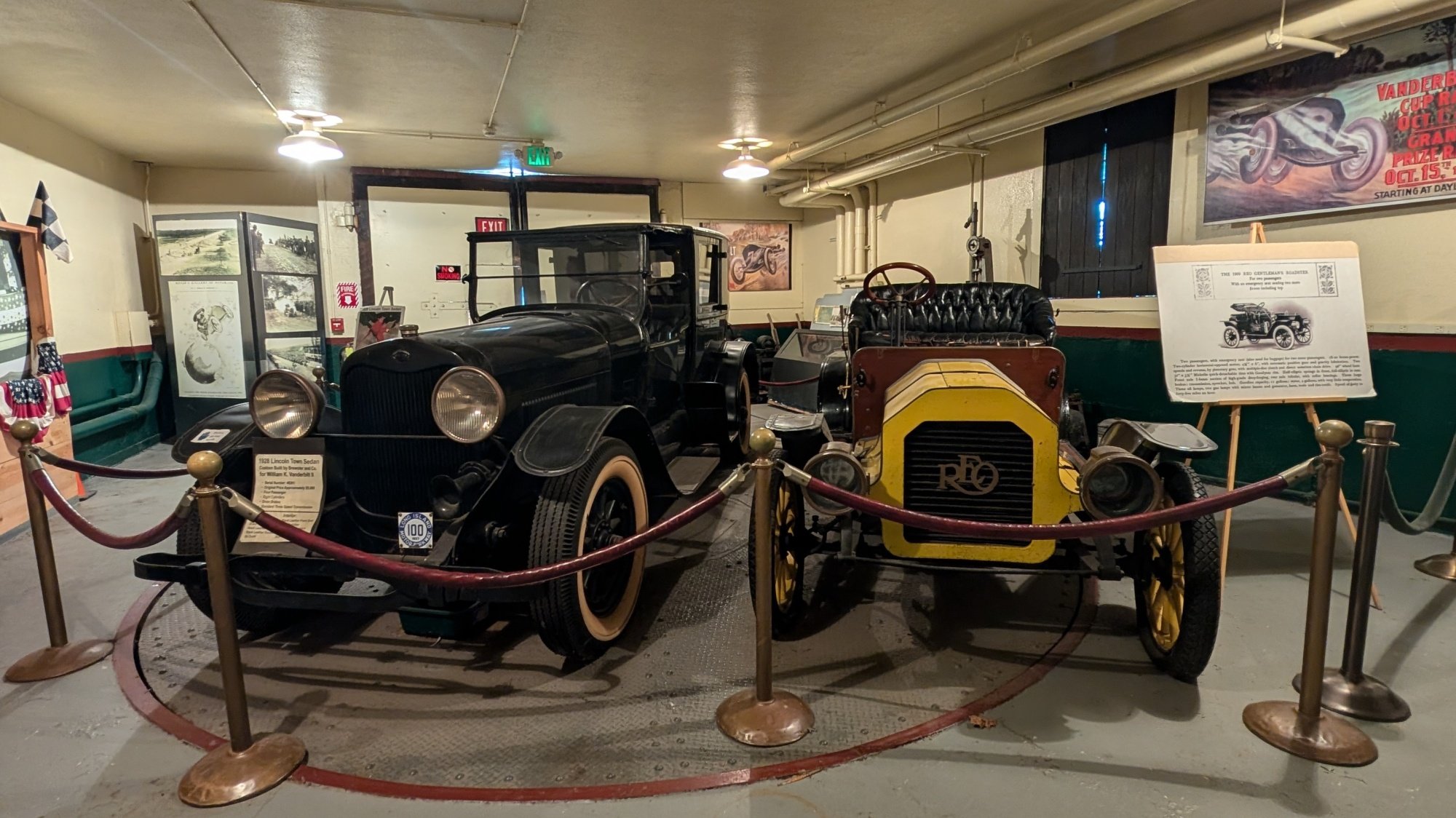 A photograph of two antique cars in a museum, taken on a Google Pixel 9 Pro XL.