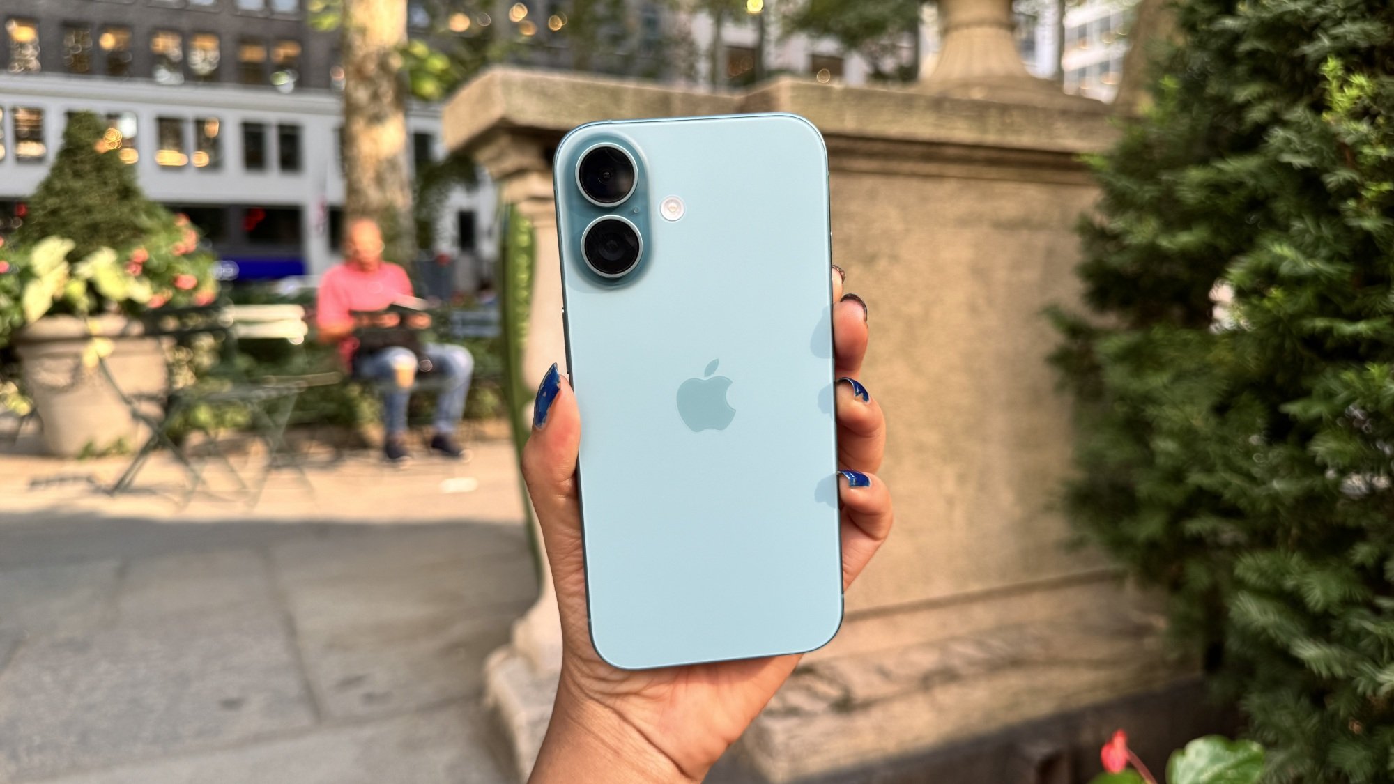 Woman holding the iPhone 16 in a park