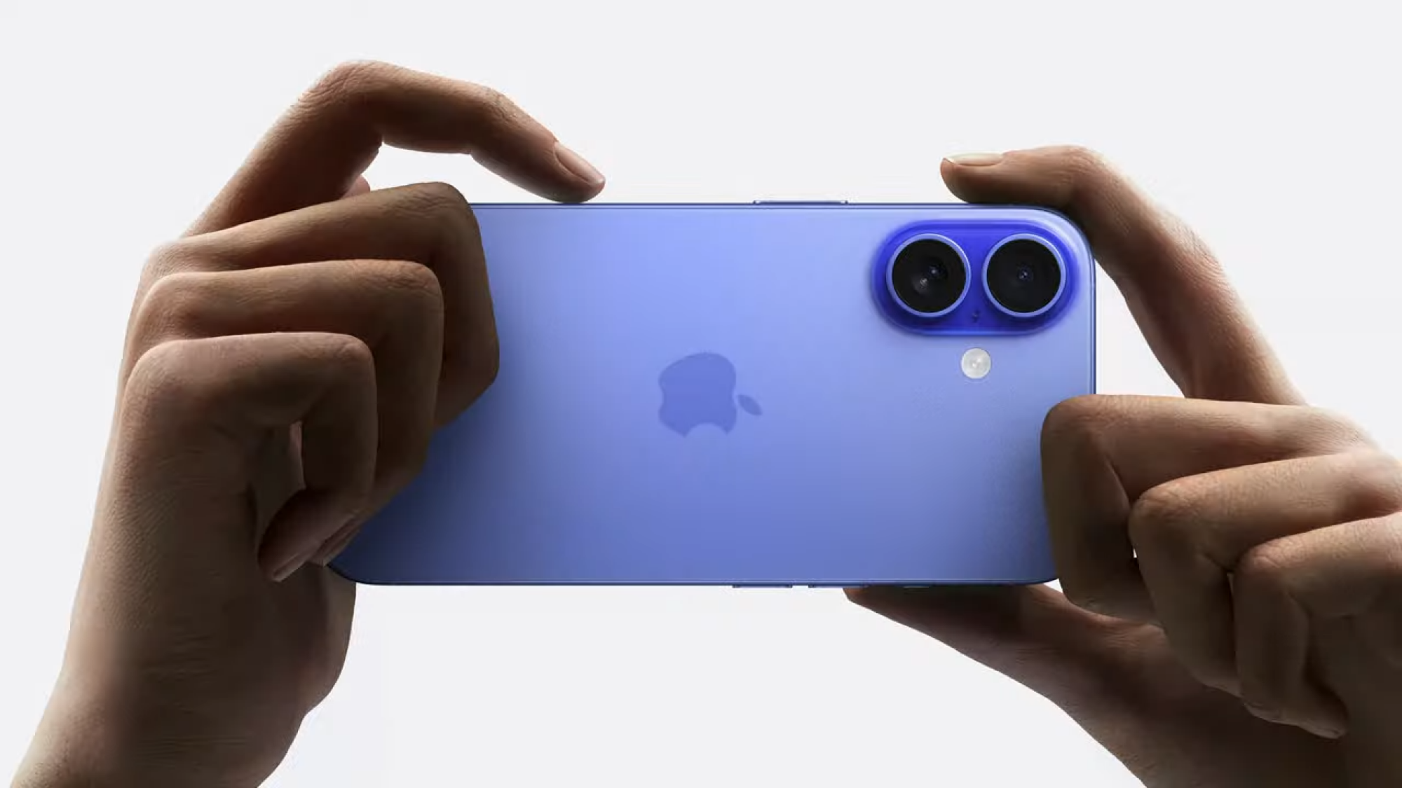 A person holding an iPhone and pressing the Camera Control button.