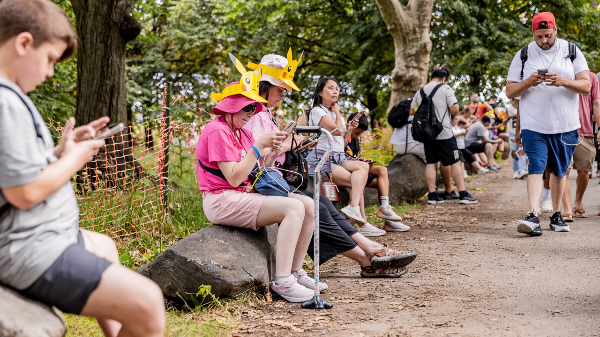 People sit on large rocks and play Pokemon GO.