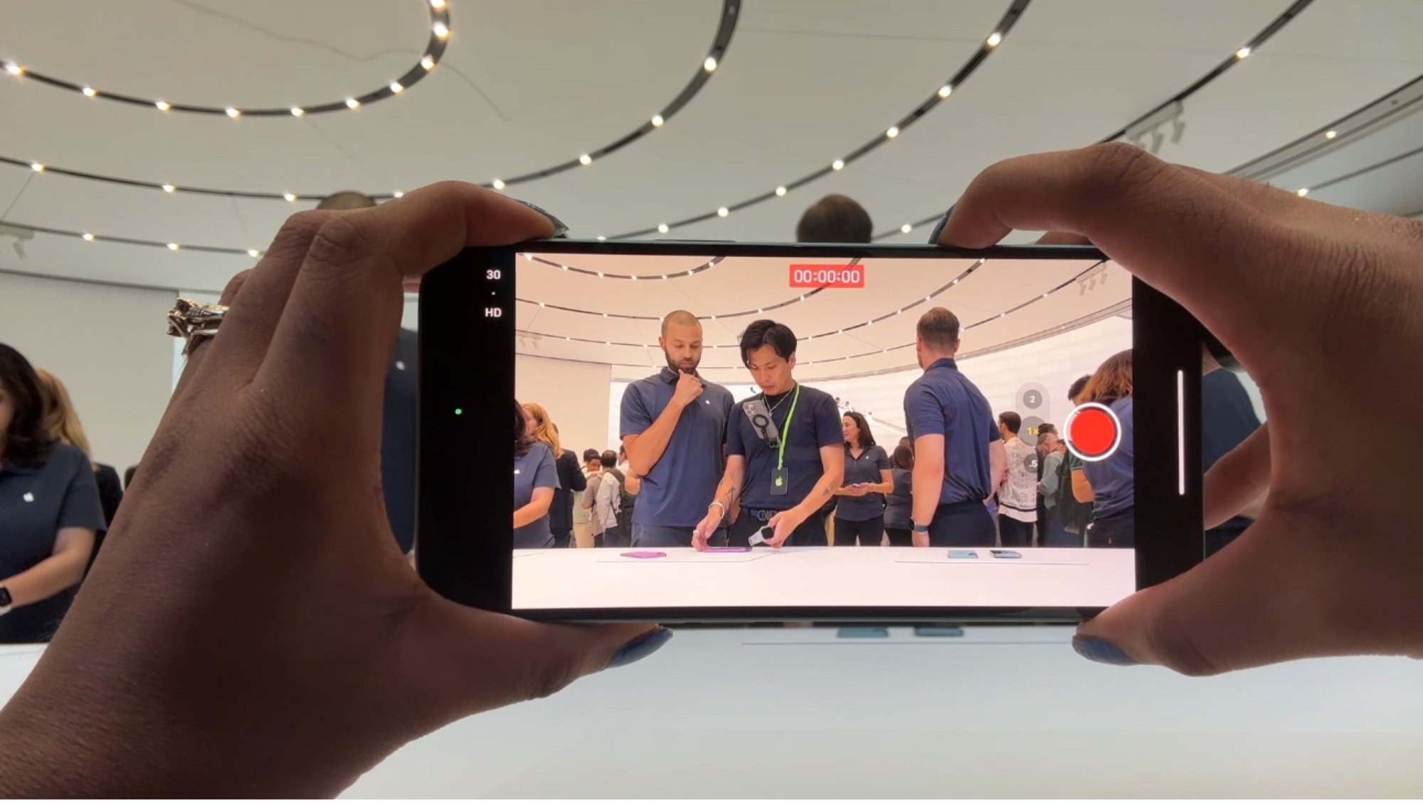 Woman recording media guests at Apple event on an iPhone