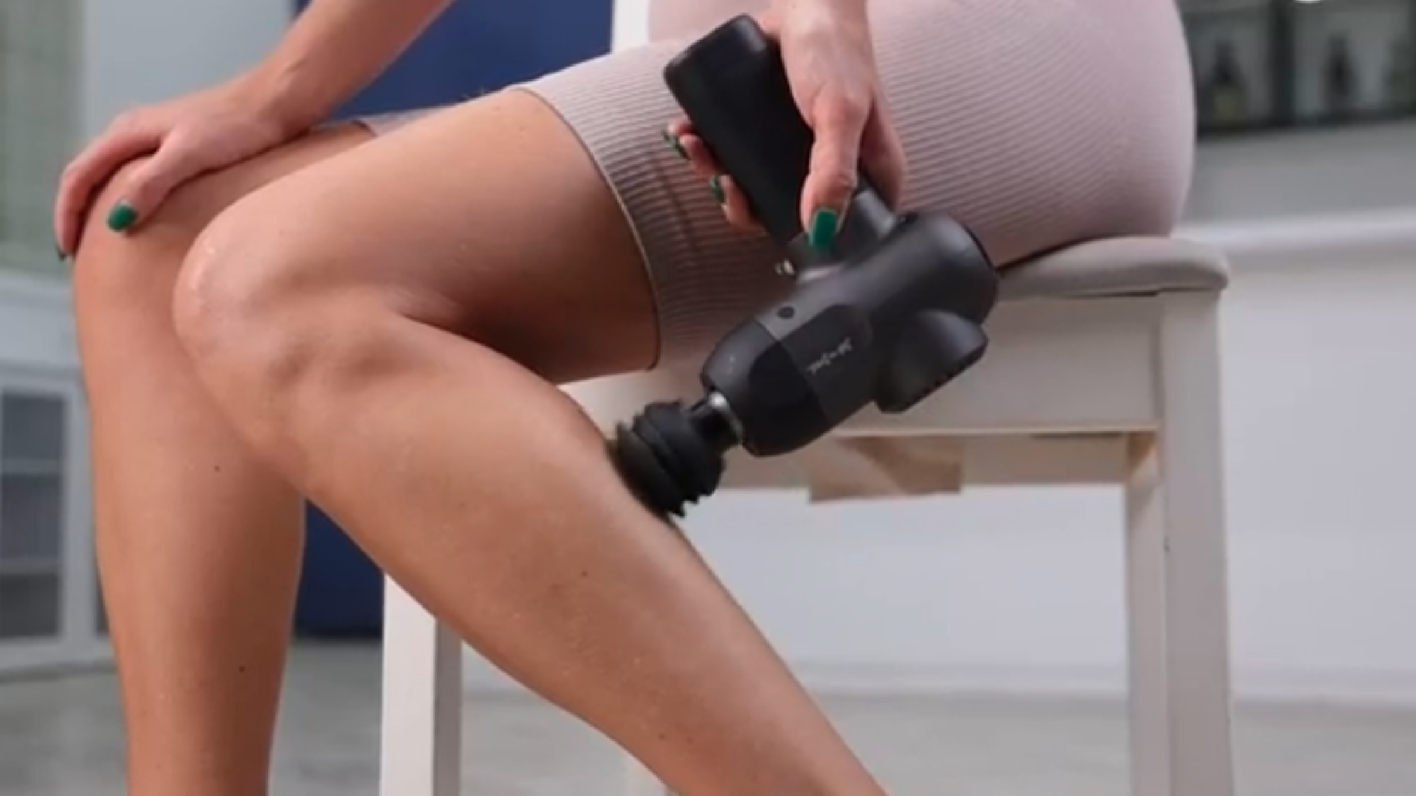 person massaging leg with massage gun