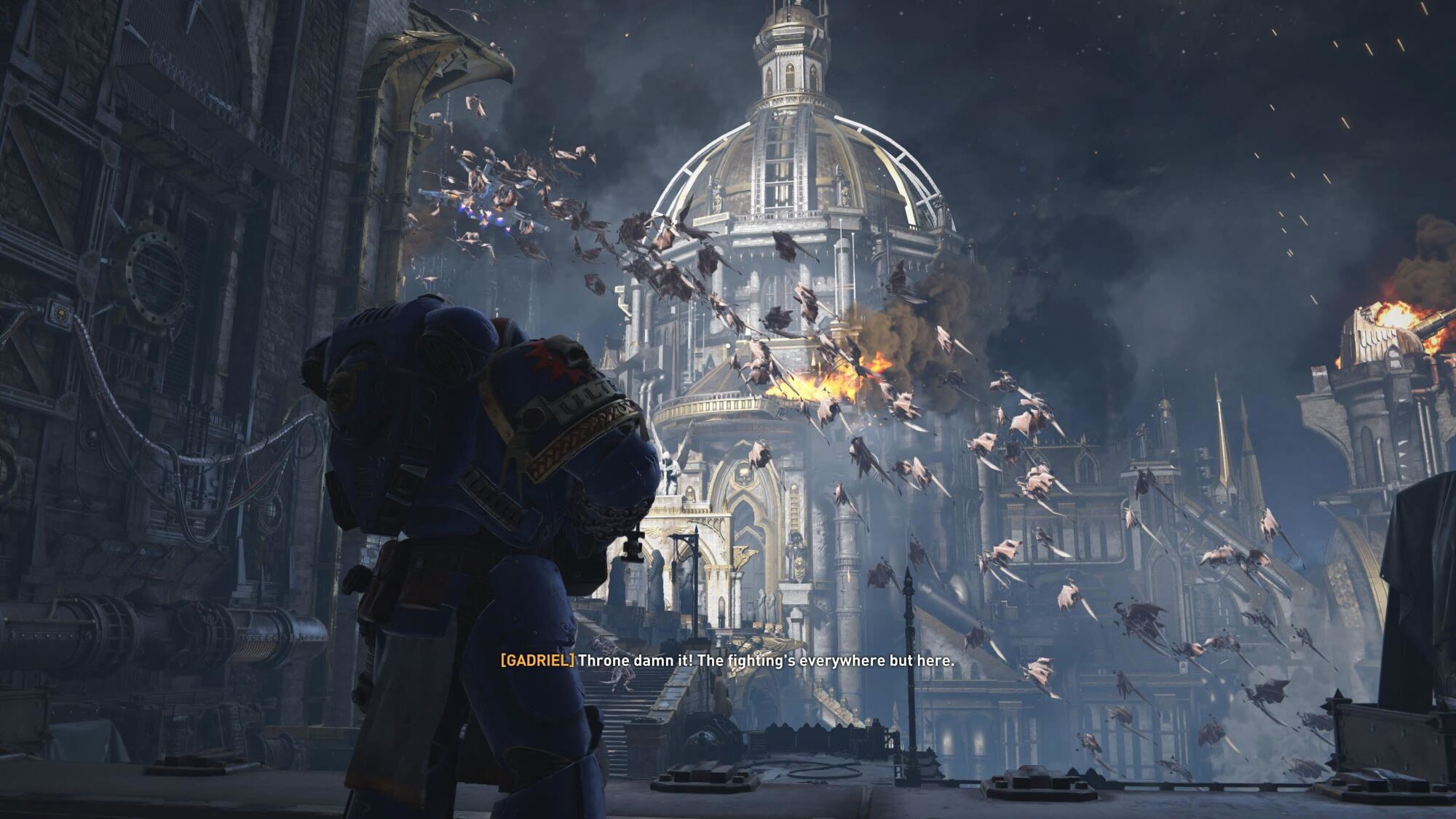 A scene from a city under attack, where a Space Marine in Ultramarine armor watches Tyranid creatures flying towards a burning cathedral.