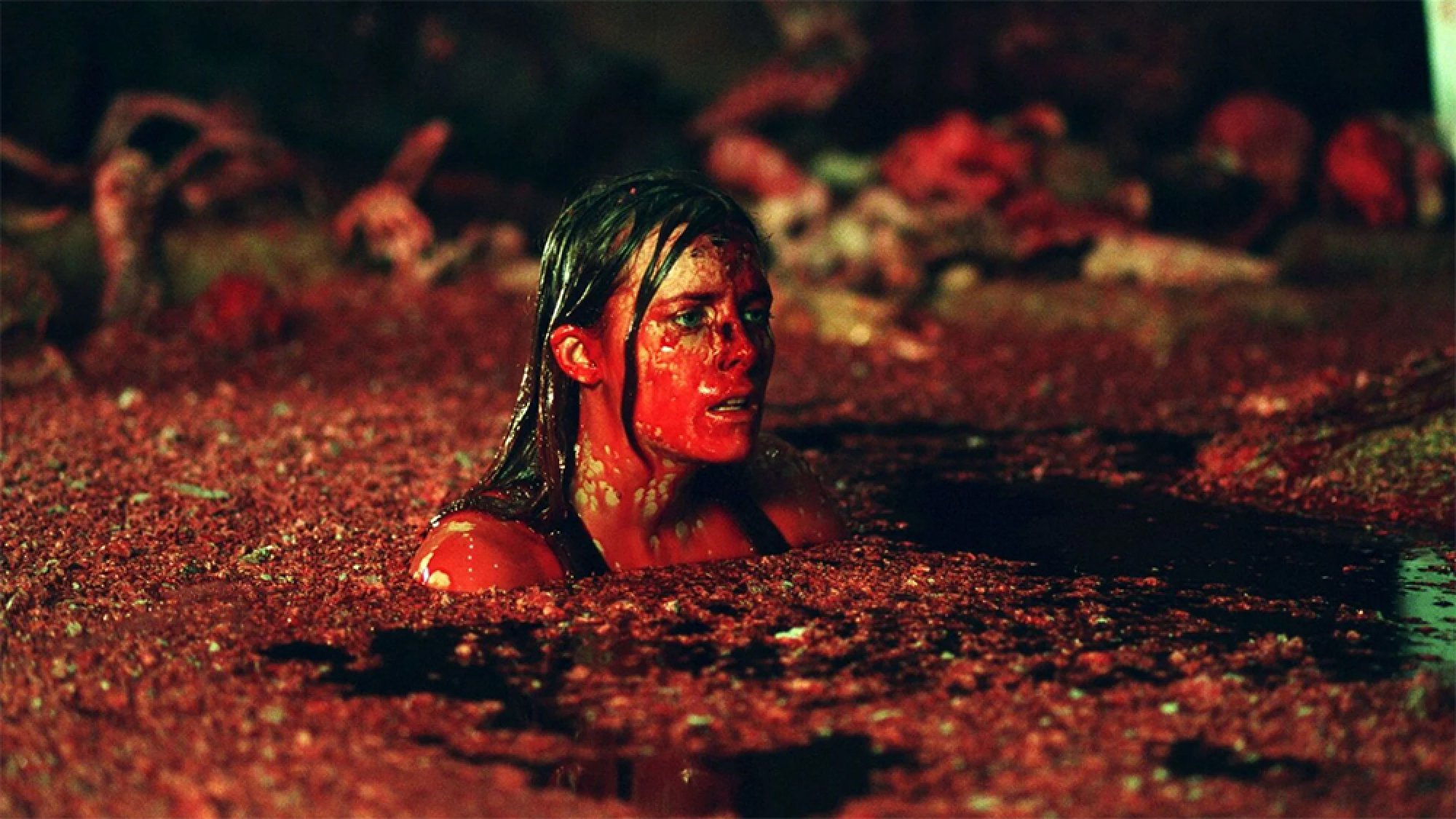 A woman swims through a sea of red in an underground cave.