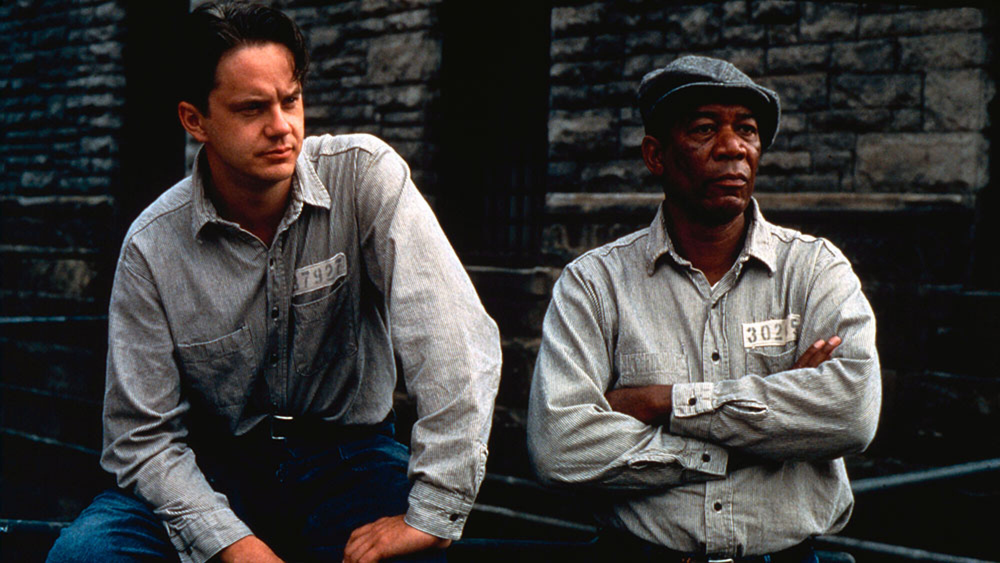 Two prison inmates sit beside each other.