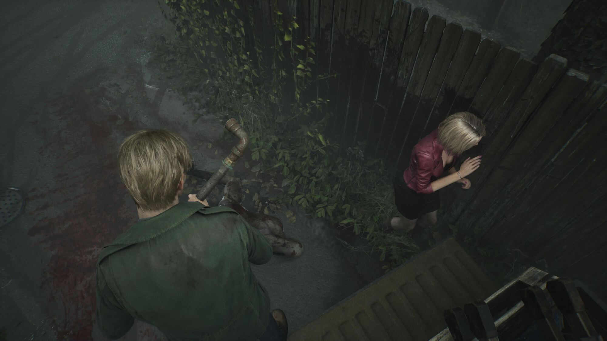 A top-down view of two characters in an outdoor setting. A man, wearing a green jacket, holds a rusty pipe while standing over a disfigured body on a bloodstained ground. To his right, a woman with blonde hair, dressed in a red jacket and black skirt, appears to be retreating in fear, leaning against a wooden fence covered with creeping vines. The scene is tense and unsettling, with dark, eerie surroundings